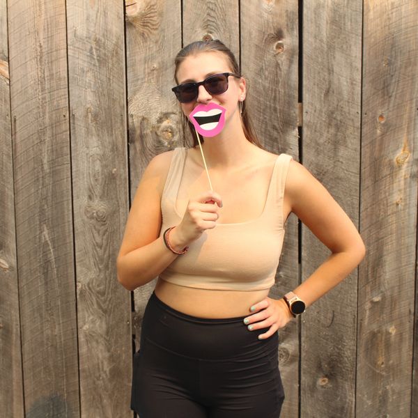 Woman posing with a funny lips prop in front of a wooden fence.
