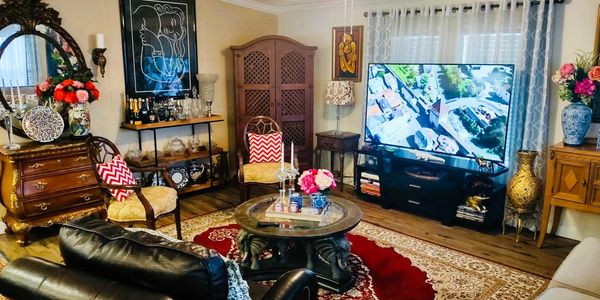 Elegant living room with vintage furniture, floral decor, and a large TV.