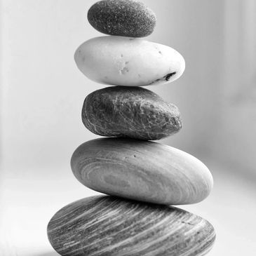 A stack of five smooth stones balanced on each other in grayscale.
