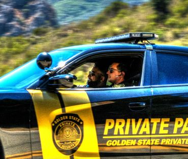 Two security officers in a Golden State Private Patrol vehicle driving on a scenic road.