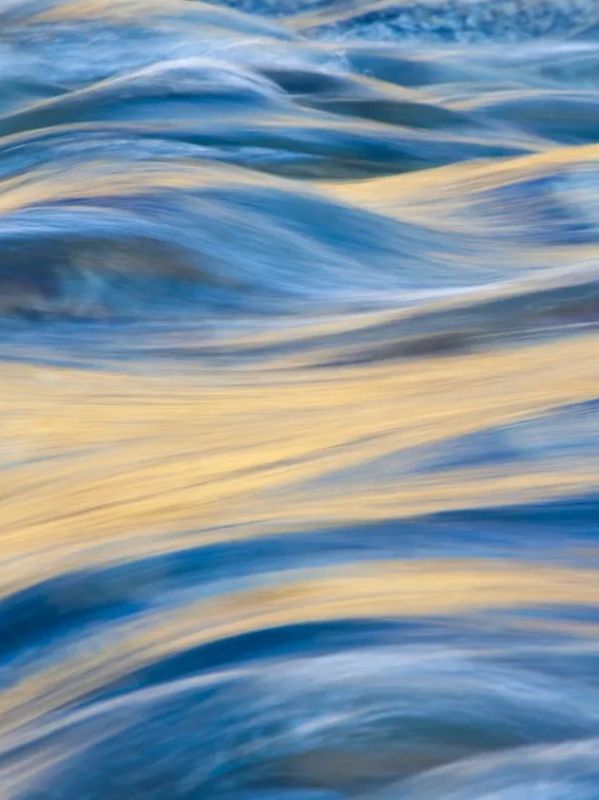 Soft waves reflecting golden sunlight on a serene water surface.