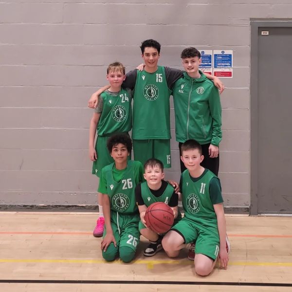Youth basketball team posing for a photo on a basketball court.