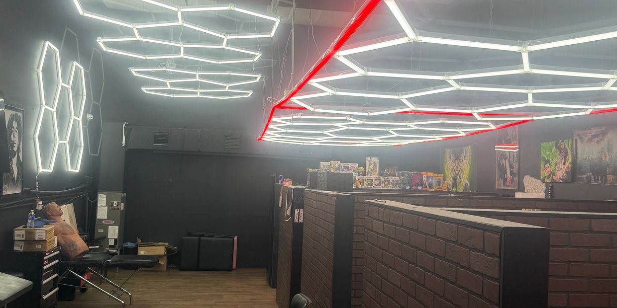 Modern tattoo studio with hexagonal ceiling lights and brick walls.