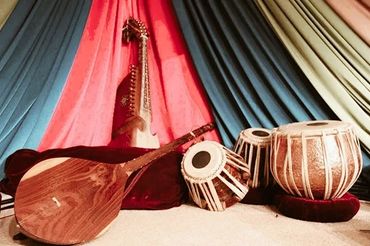 Traditional Indian musical instruments displayed against colorful drapes.