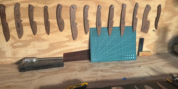 Wooden knife templates numbered and labeled, arranged on a wall above a workbench.