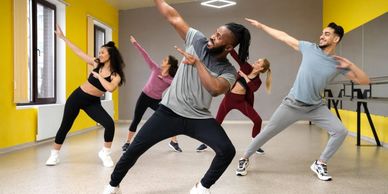 Group dance class striking a dynamic pose in a bright studio.