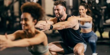 Three people doing squats together in a gym workout class.