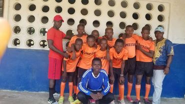 Youth soccer team posing in matching orange uniforms with coaches.