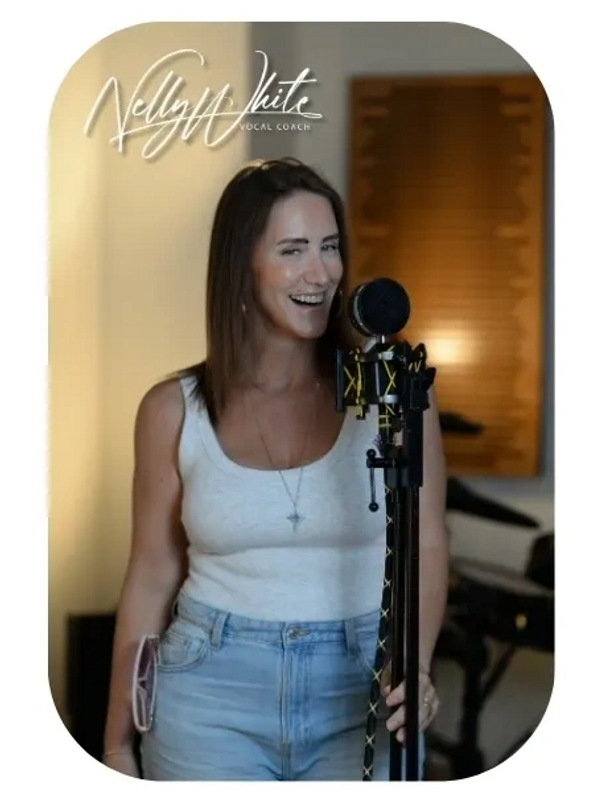 A woman singing into a microphone, smiling warmly.