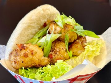 Fried chicken bites with green onions and lettuce in a soft bun.