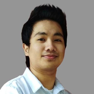 Portrait of a young man with a confident smile against a plain gray background.