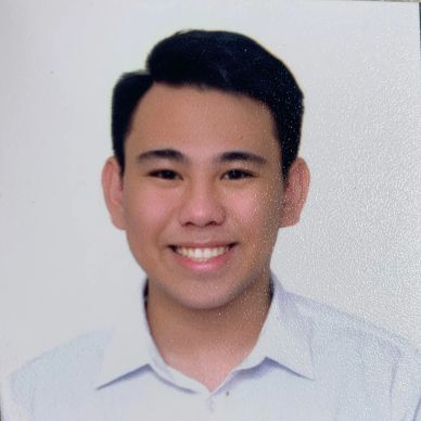 Young man smiling in a formal white shirt against a plain background.