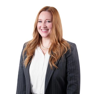Professional woman in business attire smiling against a white background.