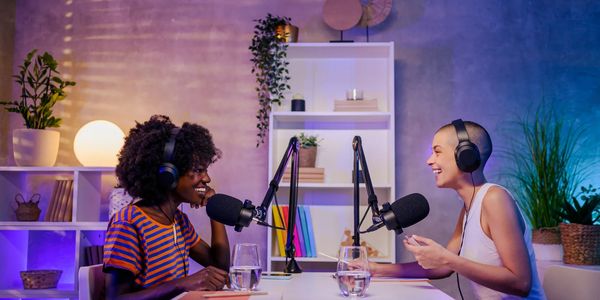Two women recording a podcast in a cozy, colorful studio.