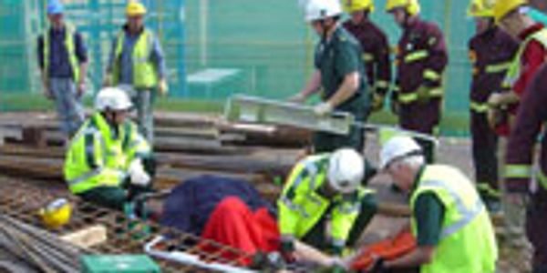 Workers with engineers equipment providing first aid to an injured worker