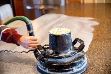 Worker using a sander to refinish the countertop