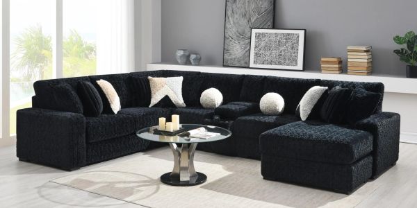 Modern black sectional sofa with light cushions in a bright living room.