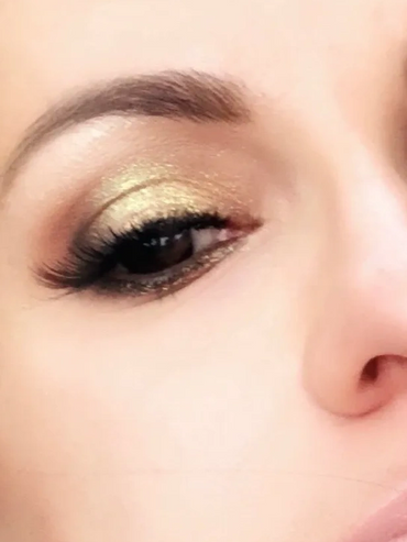 Close-up of a face with shimmering gold eyeshadow and defined lashes.