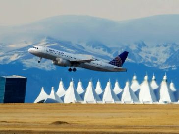 A plane taking off with snowy mountains in the background.