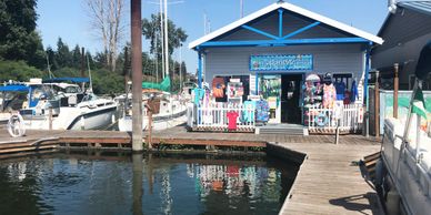 A blue gift shop by a marina with boats docked nearby.