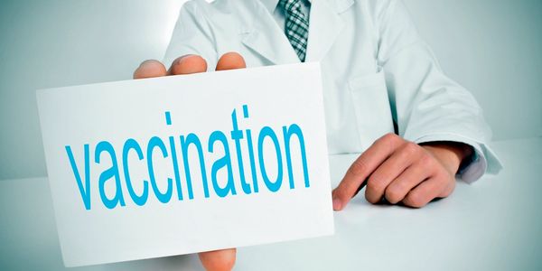 Image of a doctor holding a card starting "vaccination"