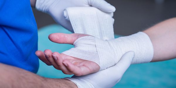 Image of a person's hand being wrapped in gauze indicating it has been injured