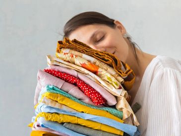 woman Mom carrying clean folded clothes, towels, sheets, linens, pillowcases, comforters, placemats