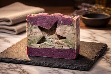 Artisan soap bar with star cutout on a textured black slate.
