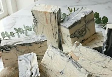 Handmade marbled soap bars arranged on a marble surface with greenery.
