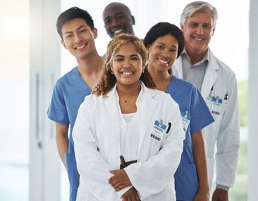 A diverse group of smiling medical professionals in a hospital setting.