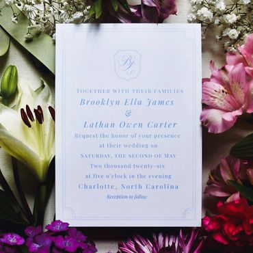 Elegant wedding invitation surrounded by vibrant flowers.