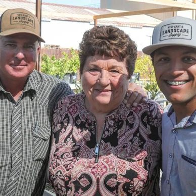 Three people smiling together outdoors.