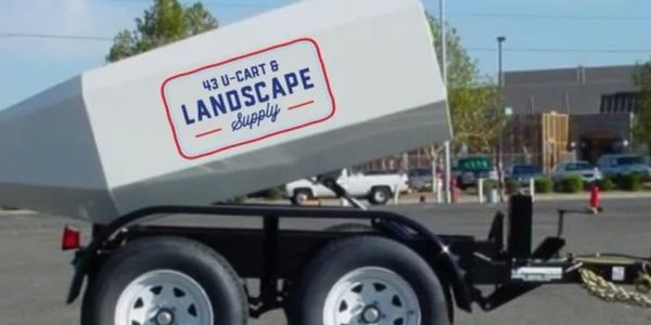 Landscape supply trailer with tilted white container.