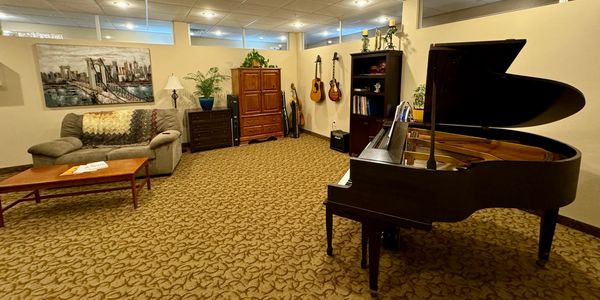 Experience Center in LHC includes baby grand piano, guitars, other instruments, sofa and plants