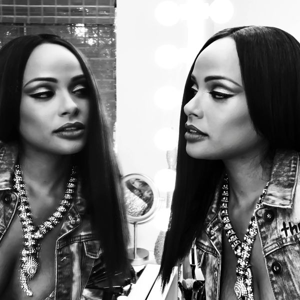 A woman with long black hair is looking at the mirror.