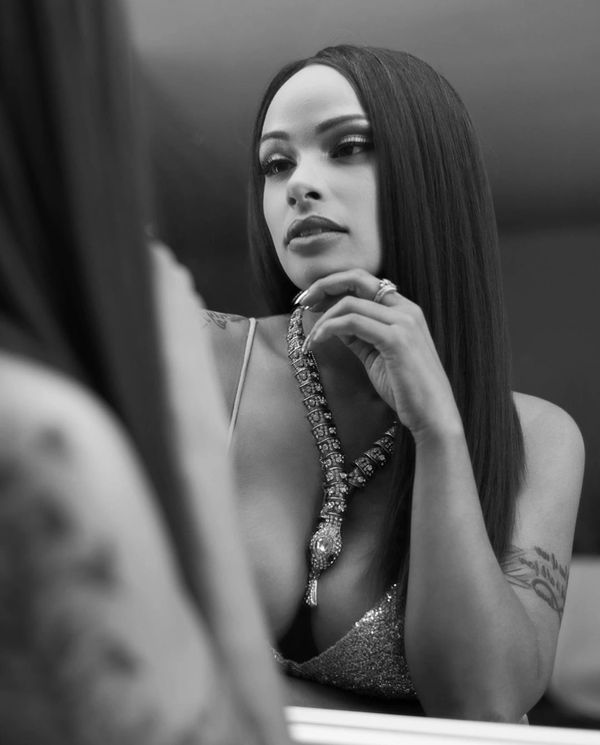 A woman with long hair and a necklace in front of a mirror.