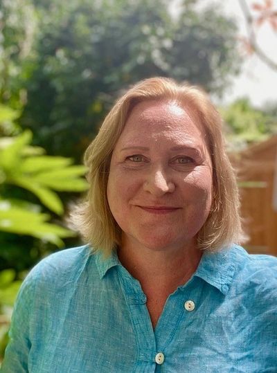 Rachel Frost is smiling and looking at the camera. She is in a garden, the background blurred.