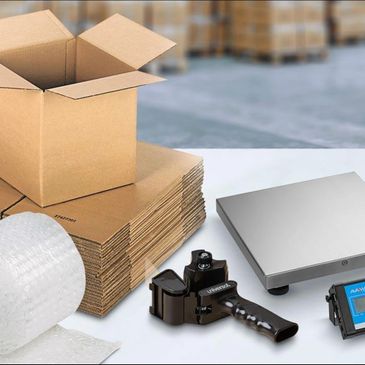 Packing supplies including cardboard boxes, bubble wrap, tape dispenser, and scale.