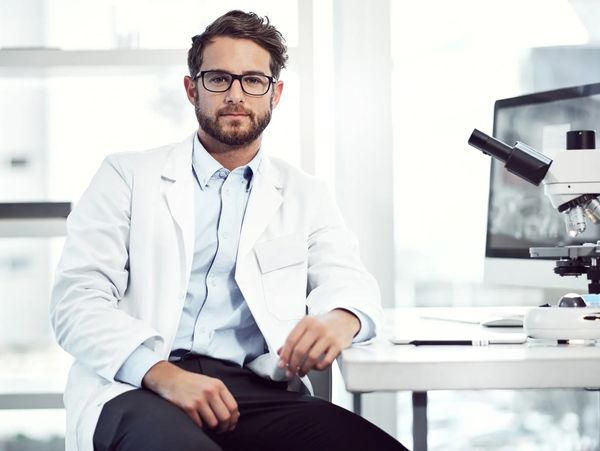 A calm, white male scientist, seating in a lab