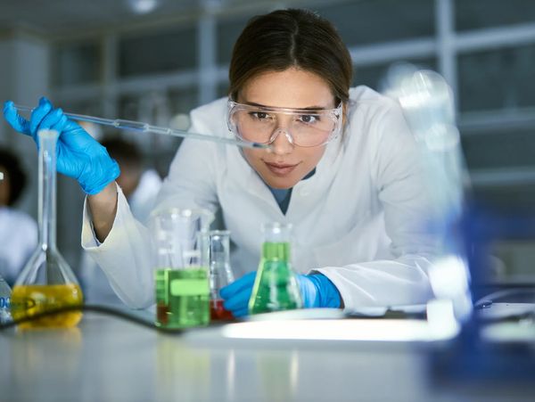 A female lab scientist working with coloured solutions in conical flask