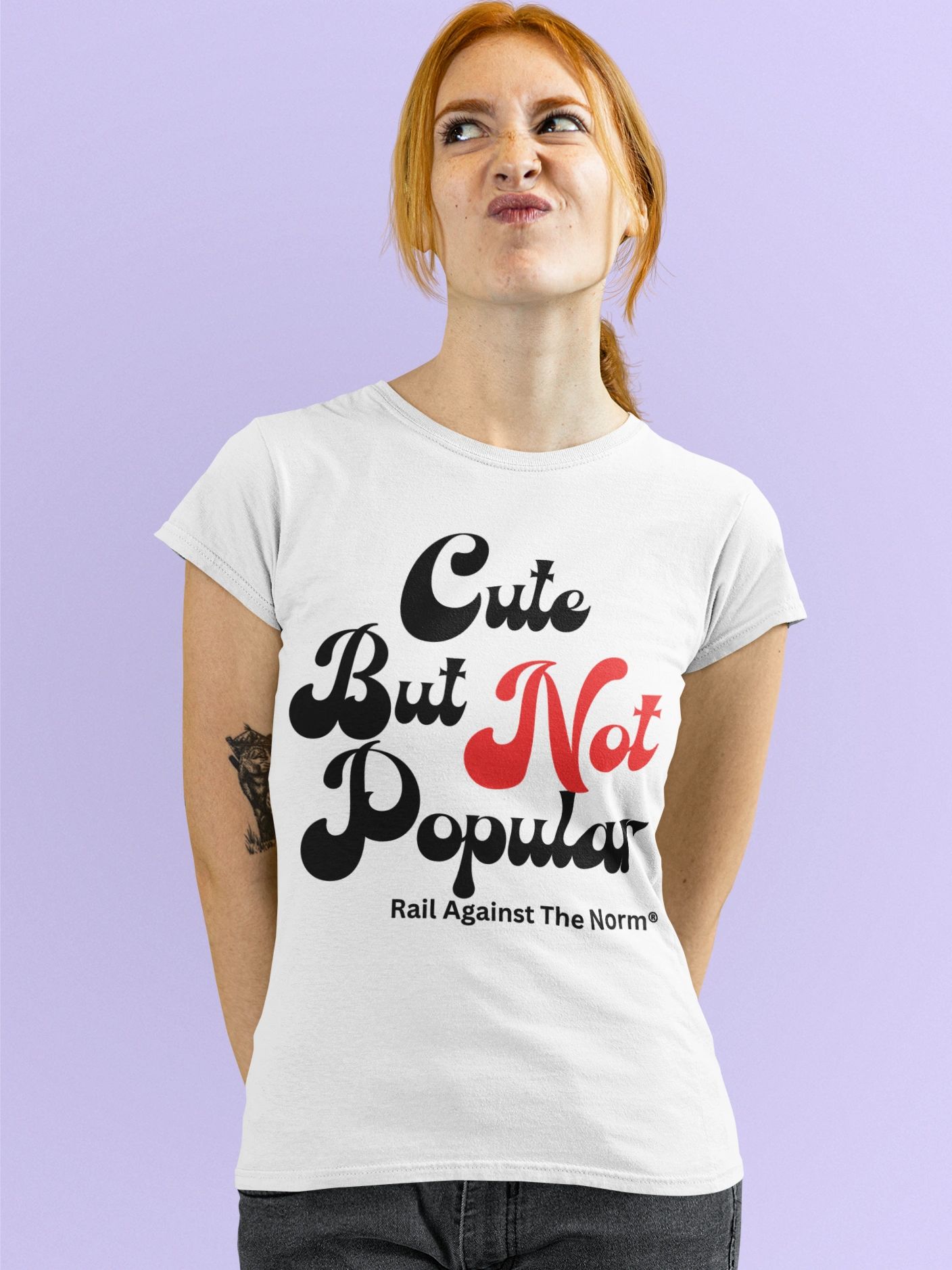 red haired woman wearing a white t-shirt is standing with hands behind her back making a face