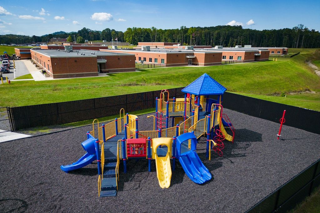 A new playground next to a brick school building.