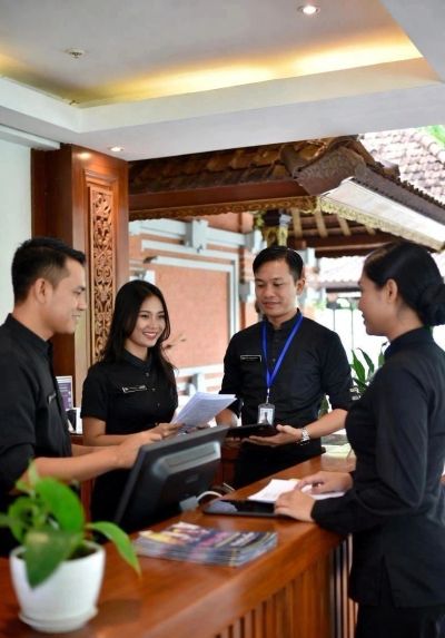 Hotel staff discussing work behind the reception desk.