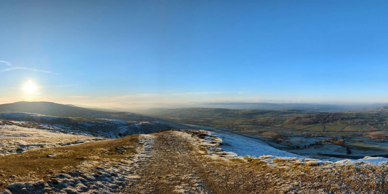 Sunrise over a frosty mountain path with clear blue skies.