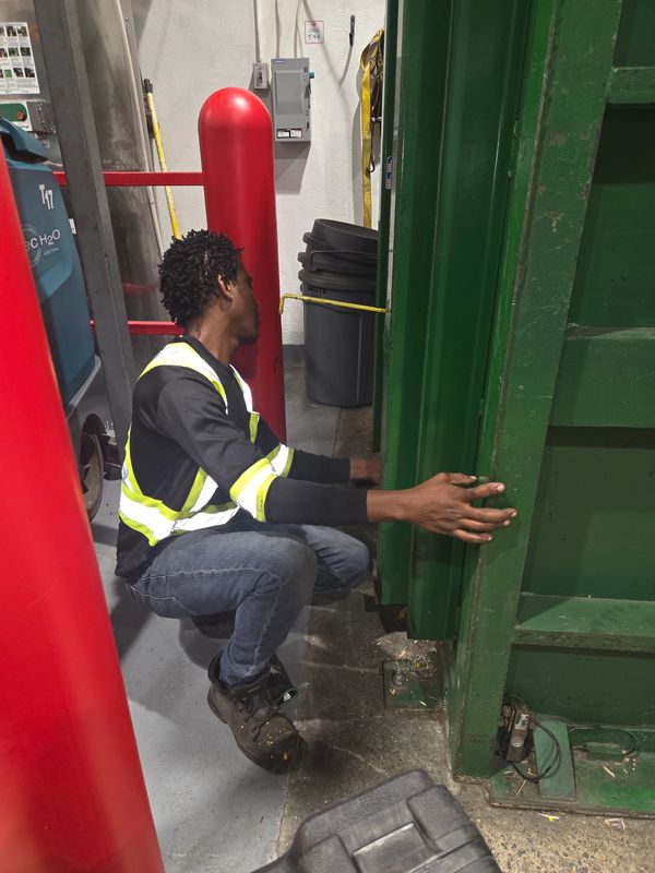 Un homme travaille près d'une grande porte verte industrielle.