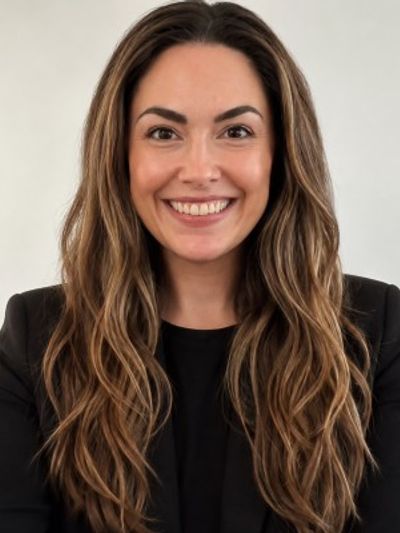 Smiling woman with long brown hair in black outfit.