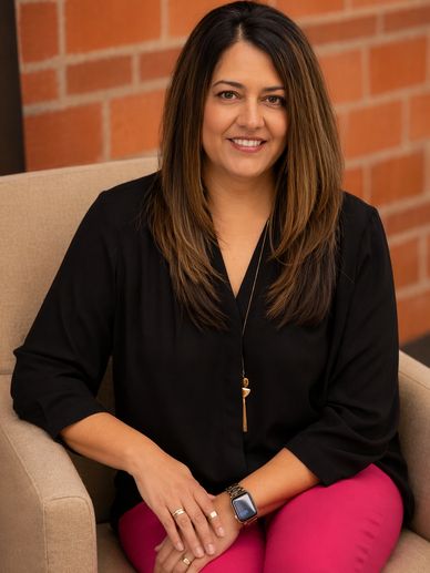 Woman sitting on a beige chair smiling.