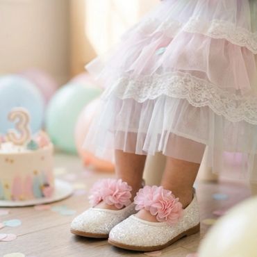 Little girl in a frilly dress and sparkly shoes at a birthday party.