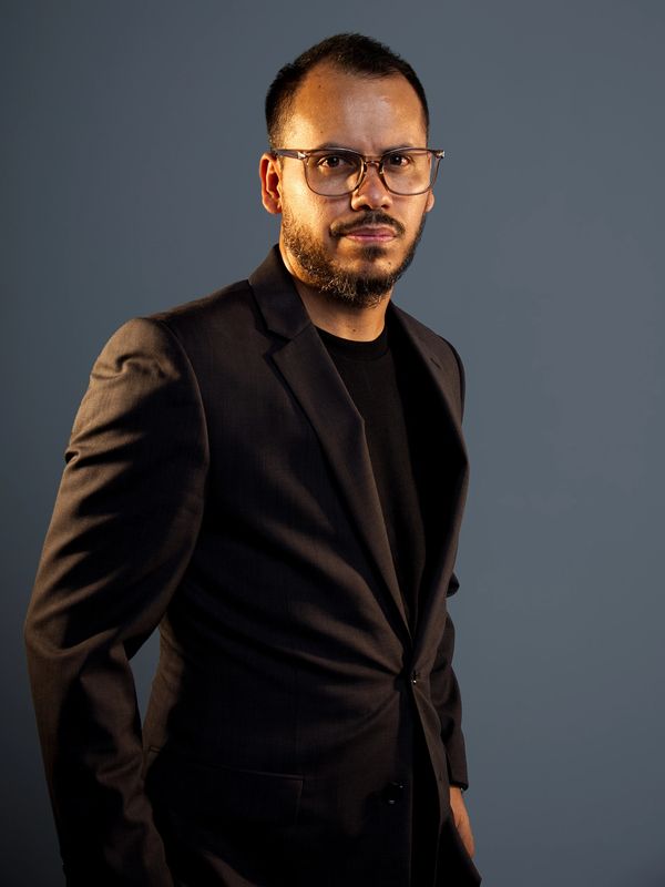 Man in glasses and suit looking confidently at camera.