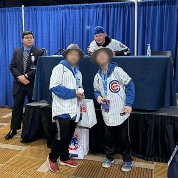 Two fans meet a Chicago Cubs player at a signing event.